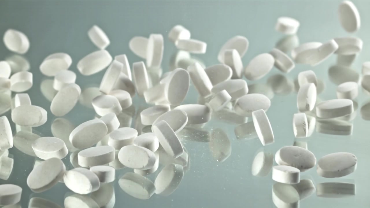 White Pills Falling and Scattering on a Reflective Surface in Slow Motion