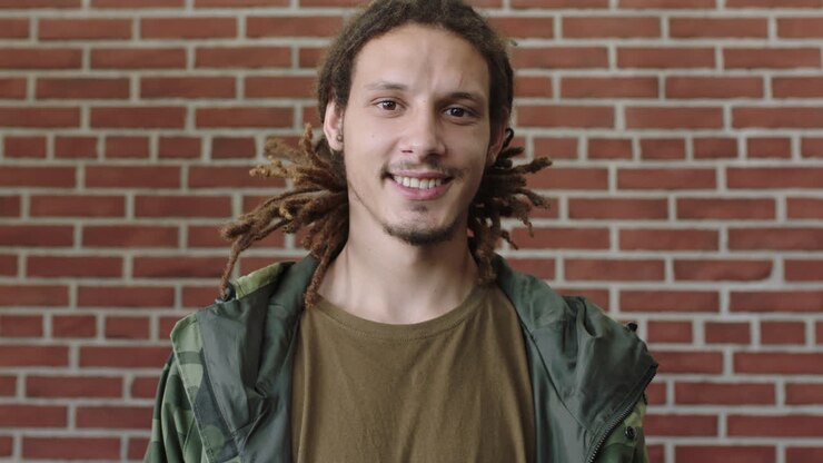 ritratto di un attraente giovane uomo di razza mista con dreadlocks sorridente felice rilassato alla telecamera