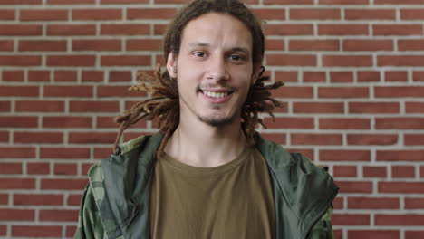 portrait of attractive young mixed race man with dreadlocks smiling happy looking relaxed at camera