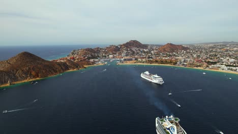 Aerial-view-of-large-passenger-ships-in-front-of-sunny-Cabo-San-Lucas,-Mexico