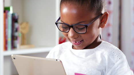 Una-Joven-Con-Gafas-Sentada-En-Un-Escritorio-En-El-Dormitorio-Jugando-En-Una-Tableta-Digital