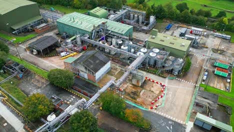 aerial video moves closer to a uk chemical factory, highlighting pipes, metal constructions, cooling towers, and chemical storage