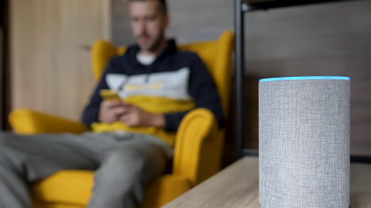 el joven interactúa con el dispositivo doméstico inteligente mientras juega por teléfono, estático