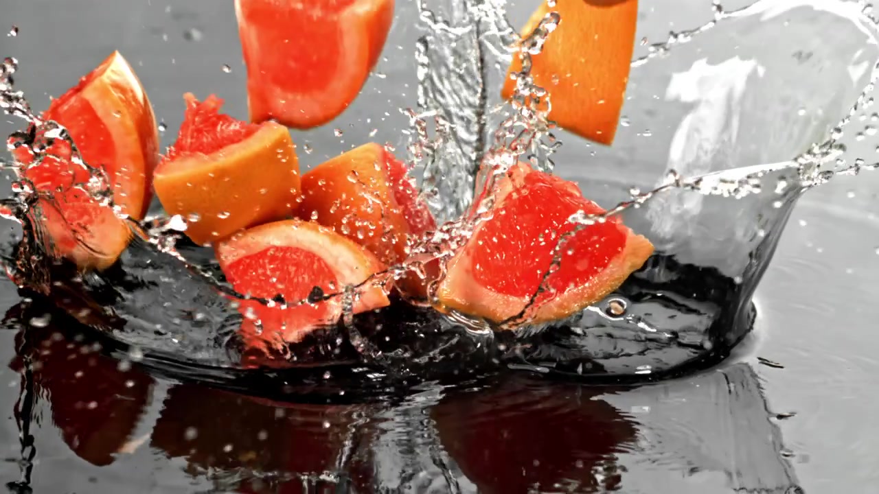 スローモーションで水中に落ちて水しぶきを上げるグレープフルーツのスライス