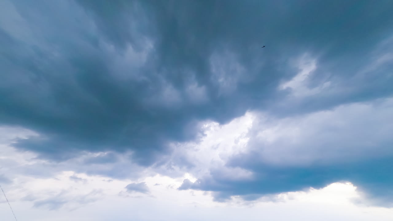 Cloud mass moving around the sky. Dark clouds spreading in the sky. Timelapse low angle view perspective.