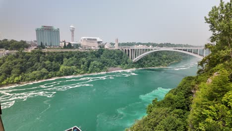 niagara river with rainbow bridge connecting usa and canada surrounded by greenery. niagara river with rainbow bridge connecting usa and canada, surrounded by greenery