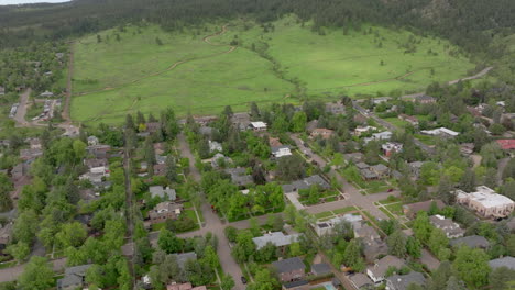 Aerial-pan-up-of-warm-sun-hitting-Boulder-Colorado-Flatiron-mountains-above-Chautauqua-Park-with-full-green-pine-trees-and-blue-skies-with-clouds-on-a-beautiful-summer-day-for-hiking