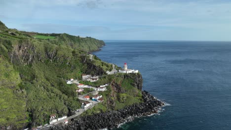 Aerial-dolly-toward-Farol-do-Arnel-lighthouse-atop-dramatic-cliffs,-Azores