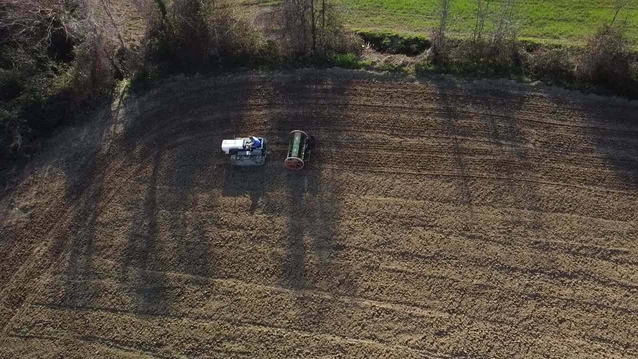 working the land at sunset with crawler tractor and seeder in the countryside, aerial shot