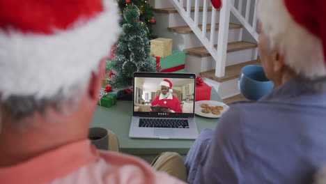 Feliz-Pareja-De-Ancianos-Caucásicos-En-Videollamada-Portátil-Con-Santa-Claus-En-Navidad