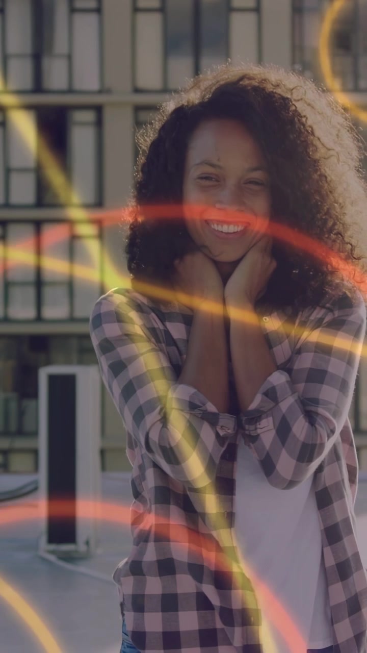 Video verticale: Donna in posa su un tetto con luci al neon, anelli rossi che le sfiorano il viso mentre si tocca i capelli, per la moda.
