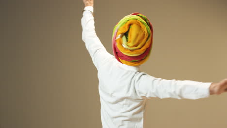 Young-handsome-indian-man-in-traditional-clothes-and-turban-smiling-while-dancing-and-spinning-around