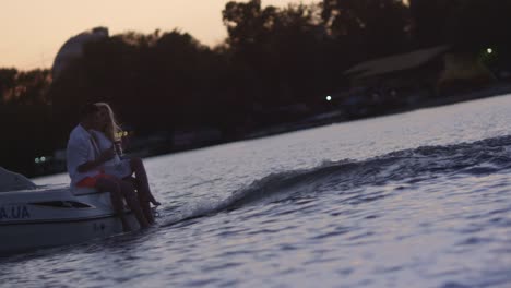 young people sitting on floating motor boat at sunset. love couple at yacht