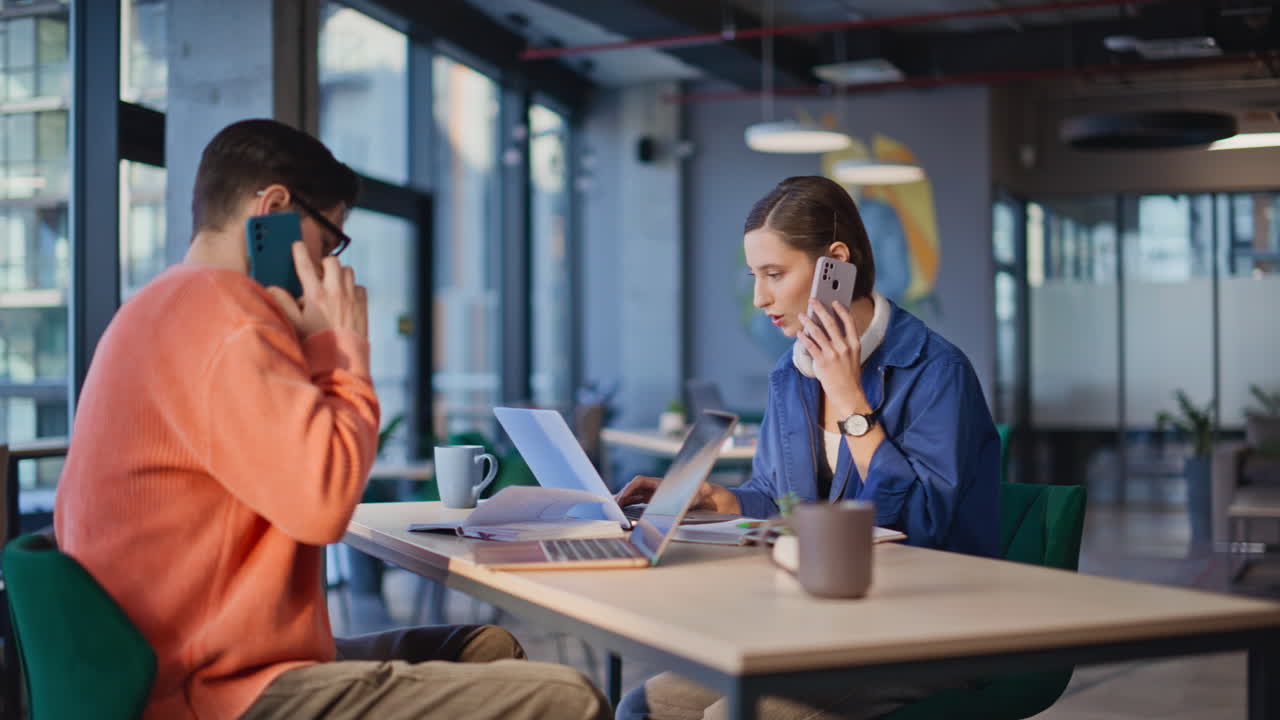 Service desk specialists calling cellphone in workplace. Two smiling managers