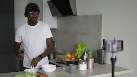 Hombre-Africano-Parado-En-La-Cocina-Graba-En-Un-Teléfono-Celular-Un-Nuevo-Video-Blog-De-Comida-Por-La-Mañana