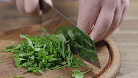 el chef corta perejil en una tabla de madera con un cuchillo de hacha