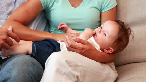 Happy-couple-on-the-couch-playing-with-their-baby-son