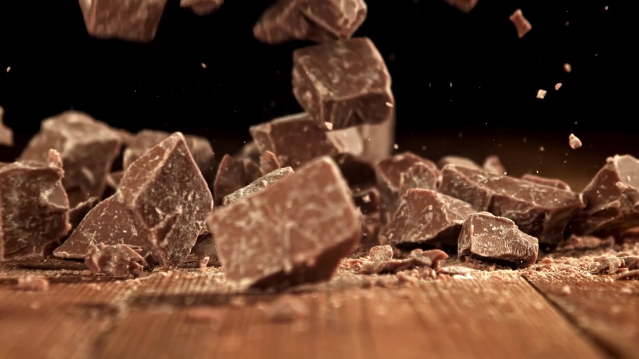 Movimento rallentato di pezzi di cioccolato che cadono su una superficie di legno