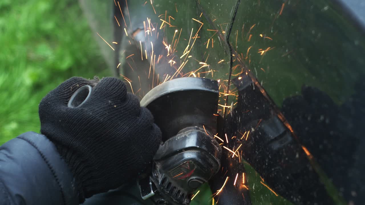 un hombre con guantes corta metal con un disco de corte. molinillo angular. trabajar con metal. pulverización de fuego. taller de reparación. mecánico de trabajos de ensamblaje mecánico