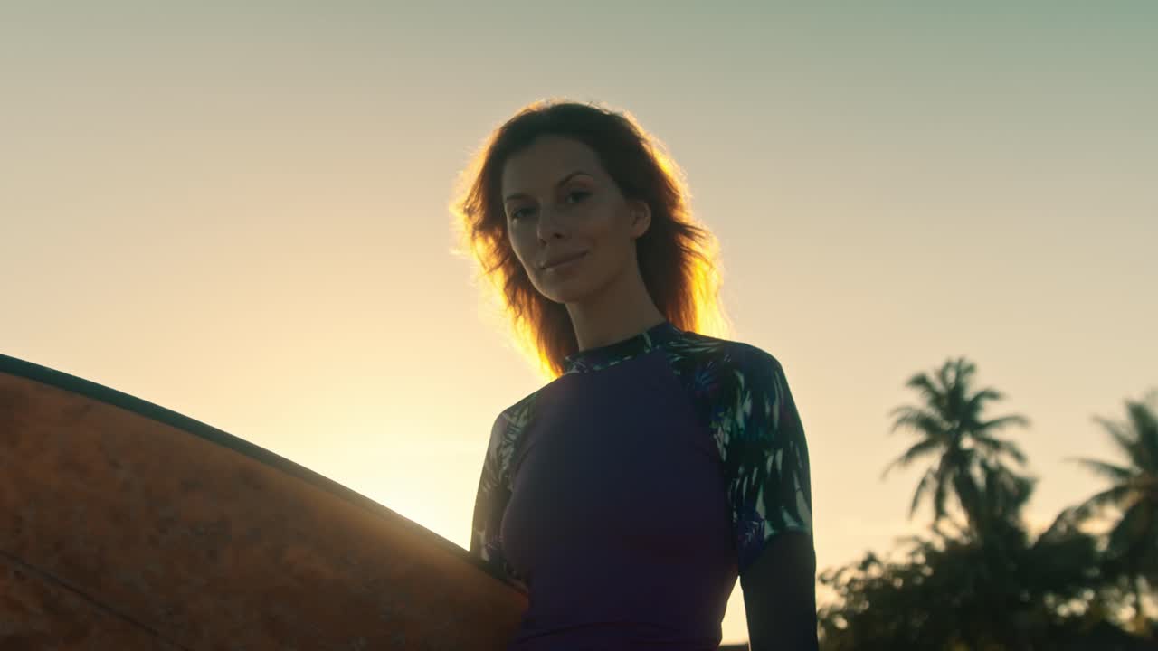 mujer con tabla de surf al atardecer