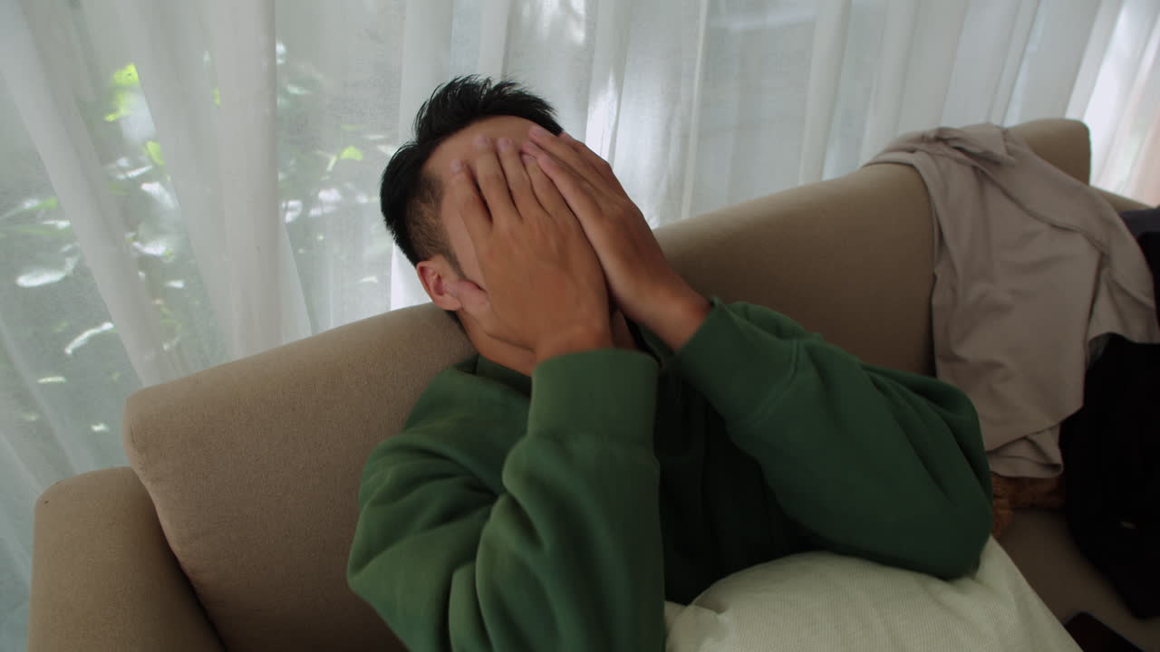 소파에 누워 있는 슬픈 남자