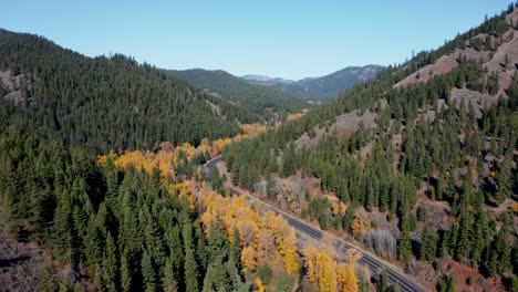 Truck-driving-on-a-wild-winding-mountain-road-through-autumn-forest-in-Washington,-USA