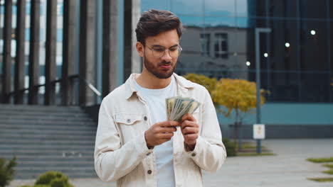 happy successful rich indian man counting money cash dollars salary profit reward bribe jackpot