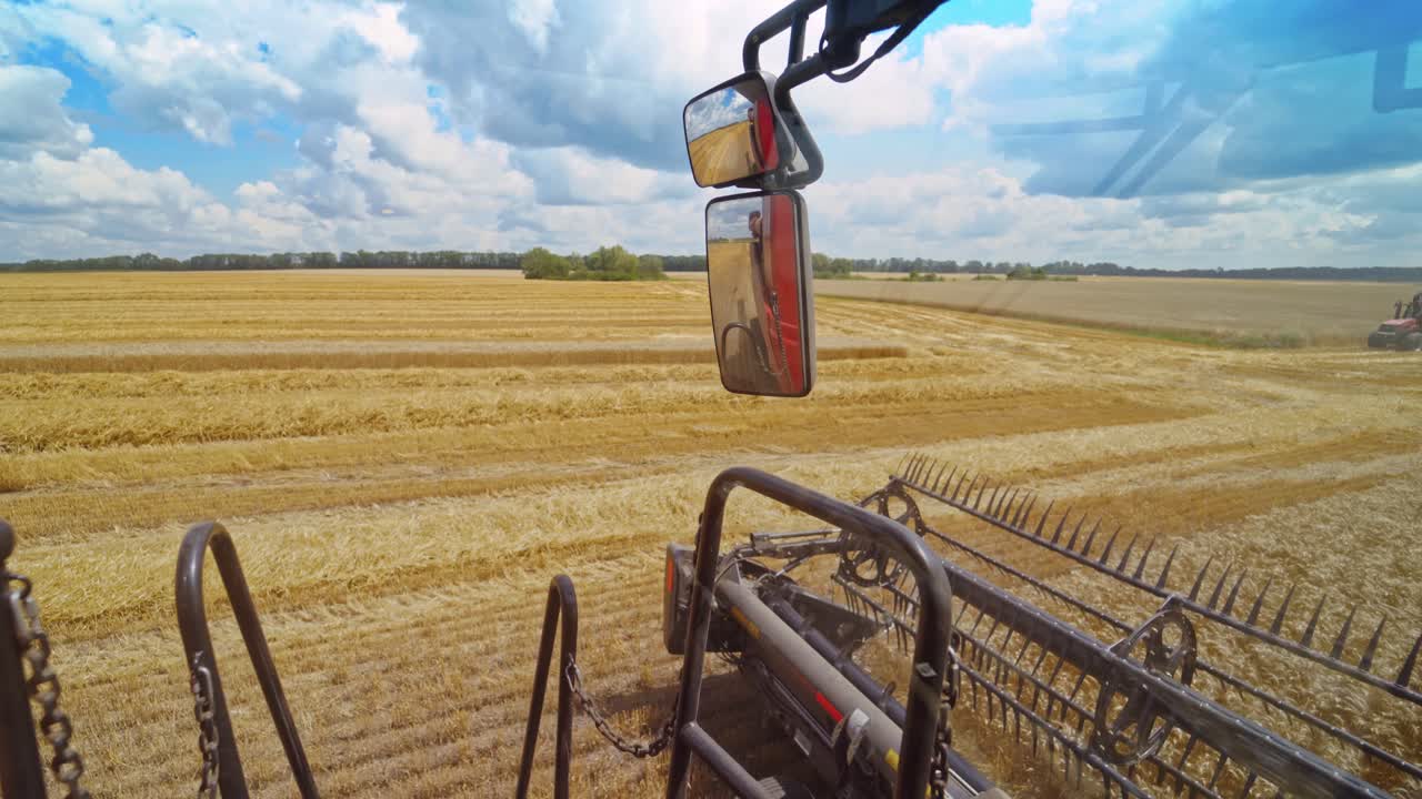 Close-up combine working in summer. Detail of grain harvester collecting ripe wheat on the field. Part of agricultural machine in a bright day.