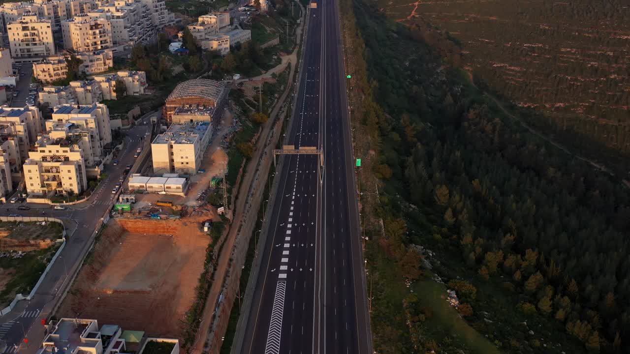 Aerial View of a Highway Adjacent to a Residential Area and Forest at Sunrise or Sunset