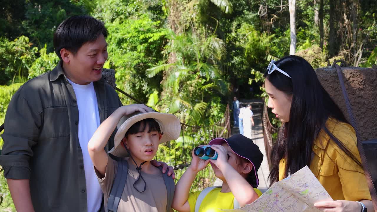 タイの緑豊かな熱帯雨林をハイキングしながら、地図を調べる親と子供たち。