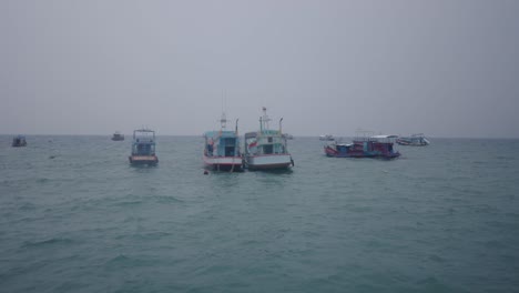 boats anchored on the sea under an overcast sky