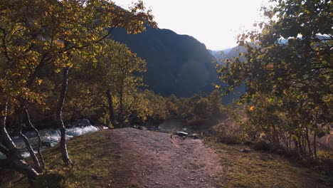 Small-drone-taking-off-from-the-ground,-flying-towards-a-beautiful-scenic-view-of-river-and-mountains