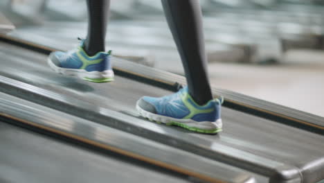 Closeup-two-pair-of-feet-moving-on-treadmill-in-fitness-gym.