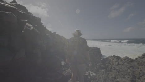 man hiking at rocky coastline with waves