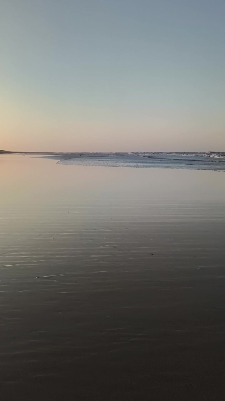 Gentle Waves Rolling onto a Calm Sandy Beach at Sunset