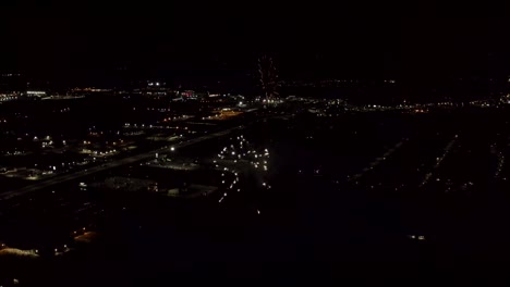 Toma-Aérea-De-Fuegos-Artificiales-Con-Luces-De-La-Ciudad-En-El-Fondo