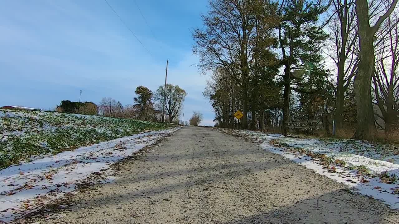 POV through the rear window at a gate and then driving on a rural gravel road on an early winter afternoon; backwards Point of View