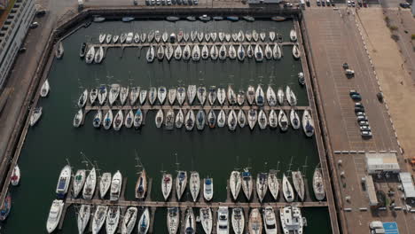 Aerial-into-overhead-top-down-view-of-luxury-white-boats-and-sailboats-docked-in-the-harbor-near-Lisbon,-Portugal