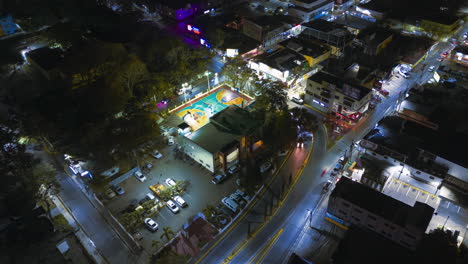 hyperlapse flight over caribbean city at night with traffic on people playing basketball game outdoors