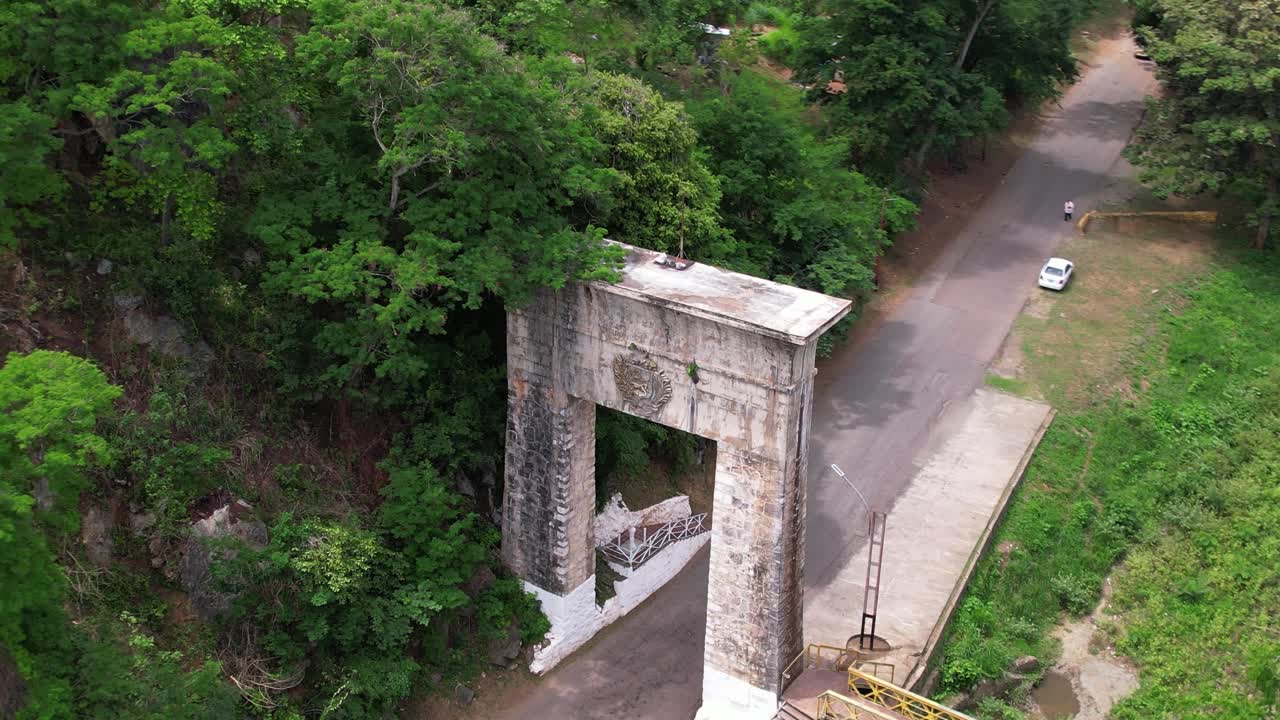 Ripresa aerea con drone che immortala il monumento storico e un vivace ponte pedonale sul fiume Guárico, fondendo storia, viaggi e natura
