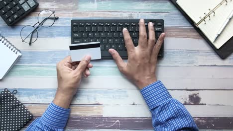 persona usando tarjeta de crédito y teclado en una mesa de madera