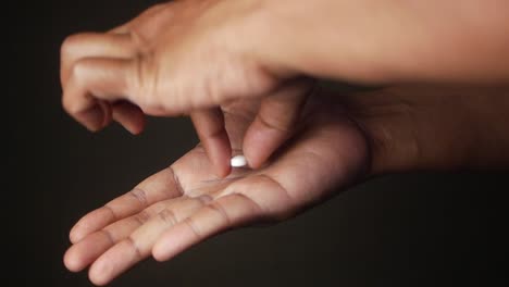 a person's hand holding a white pill