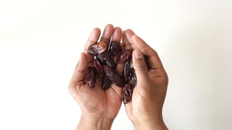 Top-view-of-many-date-fruit-on-hand-on-white-background