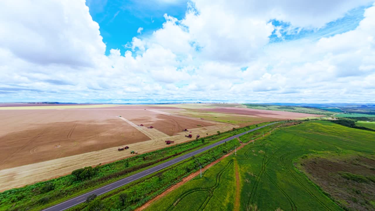 Capturing an aerial view of soybean harvesting in the rural landscape of São João da Aliança, Goiás, Brazil, highlighting vibrant agricultural activity beneath a cloudy sky