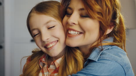 portrait shot of the lovely pretty mother and daughter hugging and smiling in front of the camera and looking happy together. at home. inside