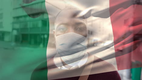bandera italiana ondeando contra el hombre que lleva una máscara facial
