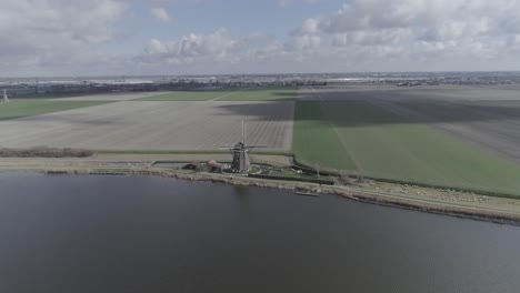 drone shot of dutch windmill on a riverbank