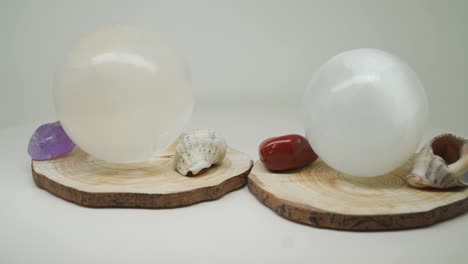 two round crystal balls on a wood with small gems and shells in between - close up shot