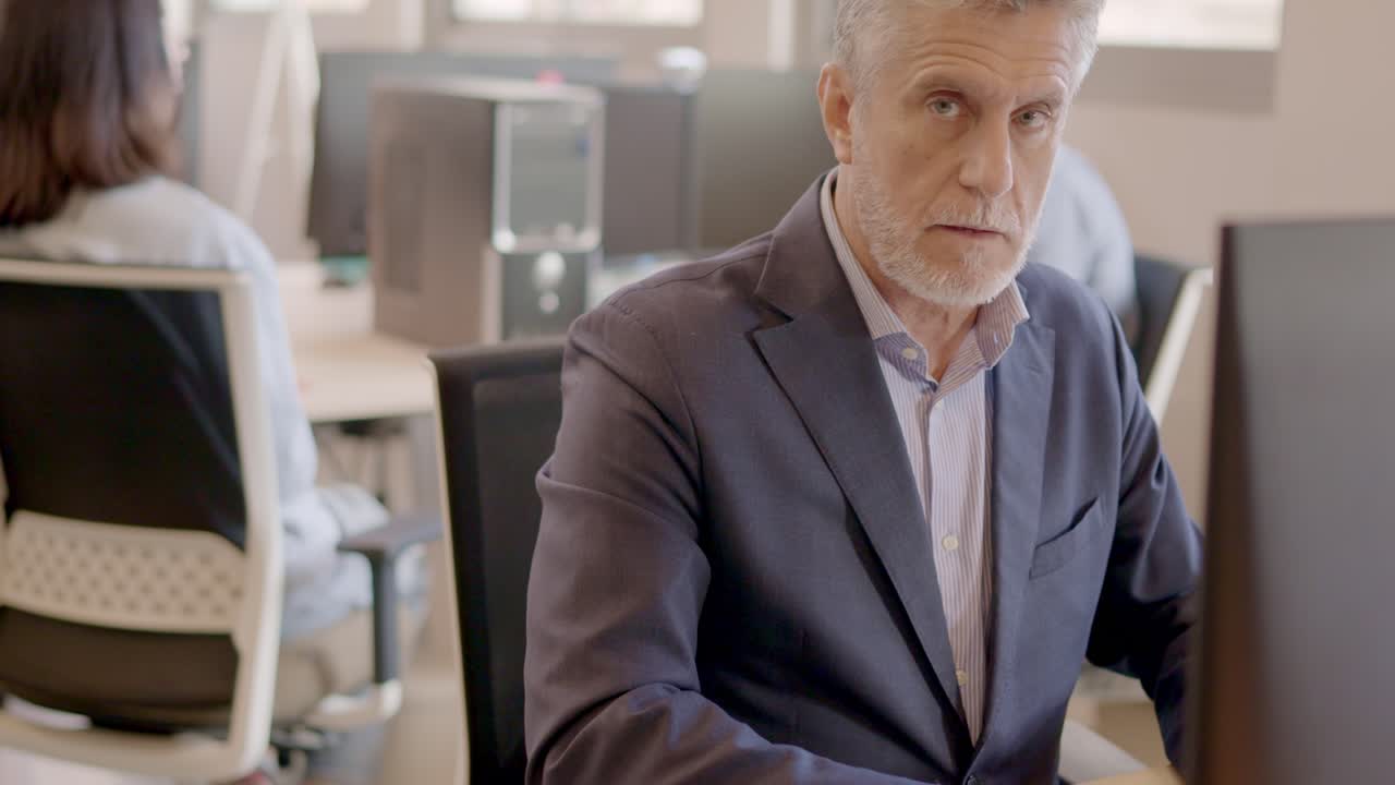 Mature man working with computer and smiling in a coworking