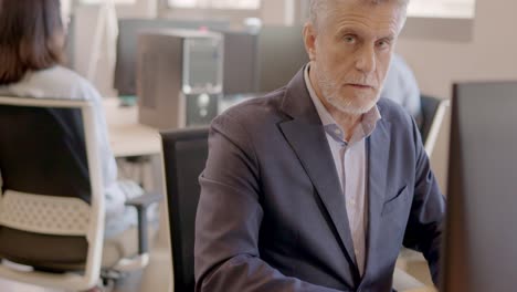 mature man working with computer and smiling in a coworking